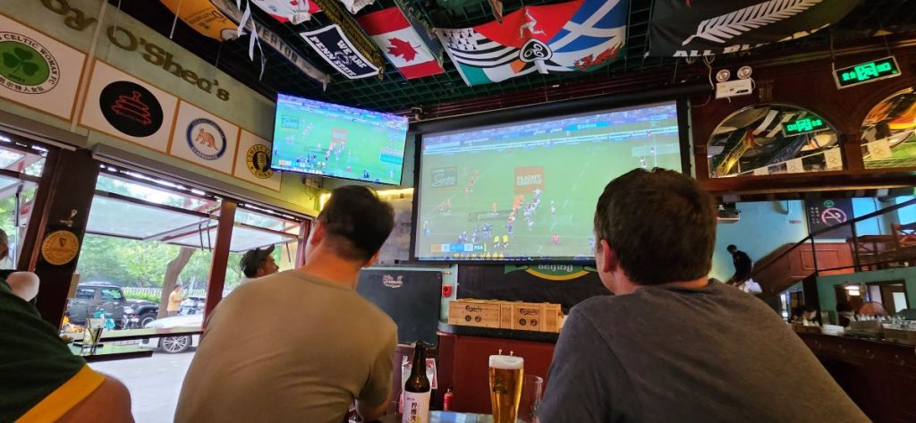 People watching a big screen TV in an Irish sports bar. Australia are playing South Africa in the 2024 edition of The Rugby Championship.